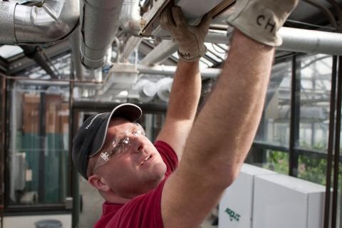 Facilities Management staff repairing an emergency exit light